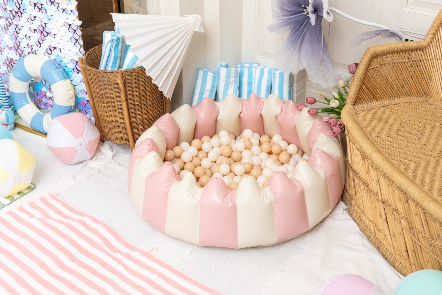 The pool party room: striped beach towels, a pink-and-cream ball pit, paper parasols, beach balls, and a giant iridescent shimmer wall