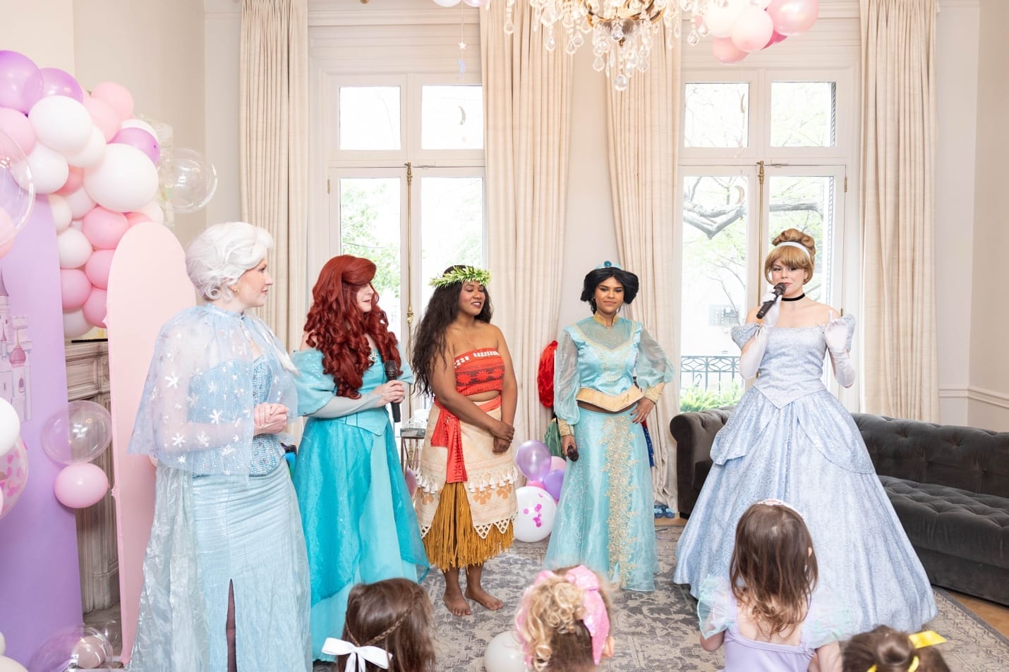 Five princess performers \u2014 Elsa, Ariel, Moana, Jasmine, and Cinderella \u2014 performing for the children